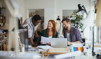 dois homens e uma mulher jovens conversam e riem | 4 dicas de arquitetura para decorar e reformar seu apartamento pequeno